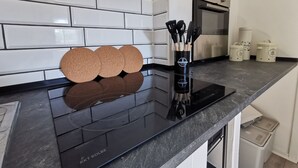 A kitchen with white subway tiles, a black countertop, a stainless steel oven, and a black induction cooktop. - Vacation home in southern Sweden-Hus Gammal Dam (pet hair free) for up to 6 people (Eringsboda)