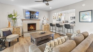 A modern living room with a fireplace, a dining area, and a kitchen. - Hideaway 4Plex! Walk to the beach, Downtown, AC! (San Clemente)