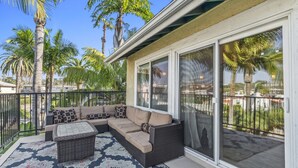 Un patio techado con un sofá modular, una mesita y un tapete estampado.
