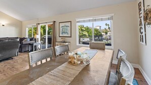A spacious living room with a large dining table, comfortable seating, a fireplace, and a view of the outdoors. - Coastal townhouse w/ AC, BBQ & shared beach access (San Clemente)