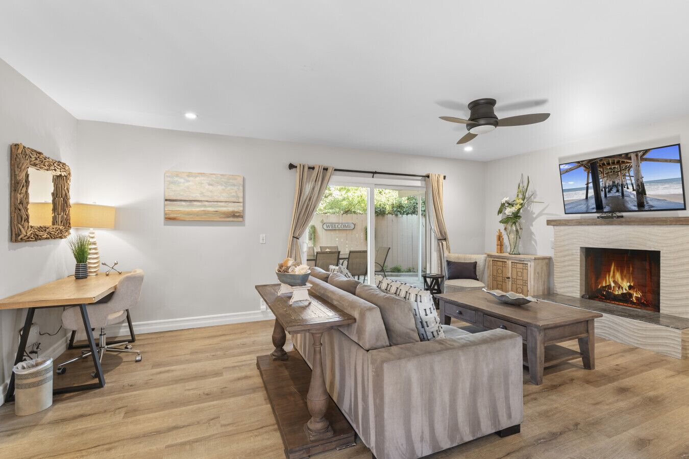 A living room with a fireplace, a sofa, a coffee table, and a TV mounted on the wall.