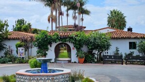 A building with a tiled roof, an archway entrance, and a fountain in the foreground. - Hideaway A- Walk to the beach, Downtown, AC! (San Clemente)