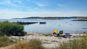 Ein Strand mit einer Reihe von Stühlen und einem Boot auf dem Wasser.
