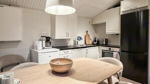 Eine moderne Küche mit weißen Schränken, einem Holztisch und einem schwarzen Kühlschrank.