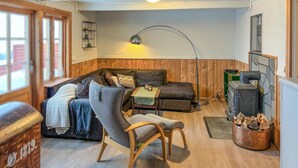 A cozy living room with a wooden floor, a sofa, a chair, a table, a lamp, and a fireplace. - Cozy home in Oppdal with house a mountain view (Oppdal)