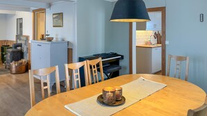 A dining area with a round wooden table, two chairs, a black lamp, and a kitchen in the background. - Cozy home in Oppdal with house a mountain view (Oppdal)