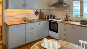 A kitchen with grey cabinets, a stainless steel sink, a stove, and a window with a view of a snowy landscape. - Cozy home in Oppdal with house a mountain view (Oppdal)