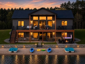 A two-story house with a balcony, a pool, and kayaks.