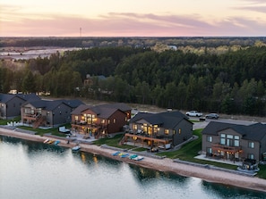 A lakeside resort with multiple cabins, a dock with kayaks, and a forested backdrop.