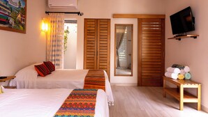 Quarto de hotel com duas camas, televisão, espelho e porta de madeira.