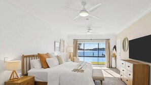 A bedroom with a large bed, a nightstand, a dresser, a TV, and a view of the water. - Private Jetty. Waterfront. Sleeps 10 (Koolewong)