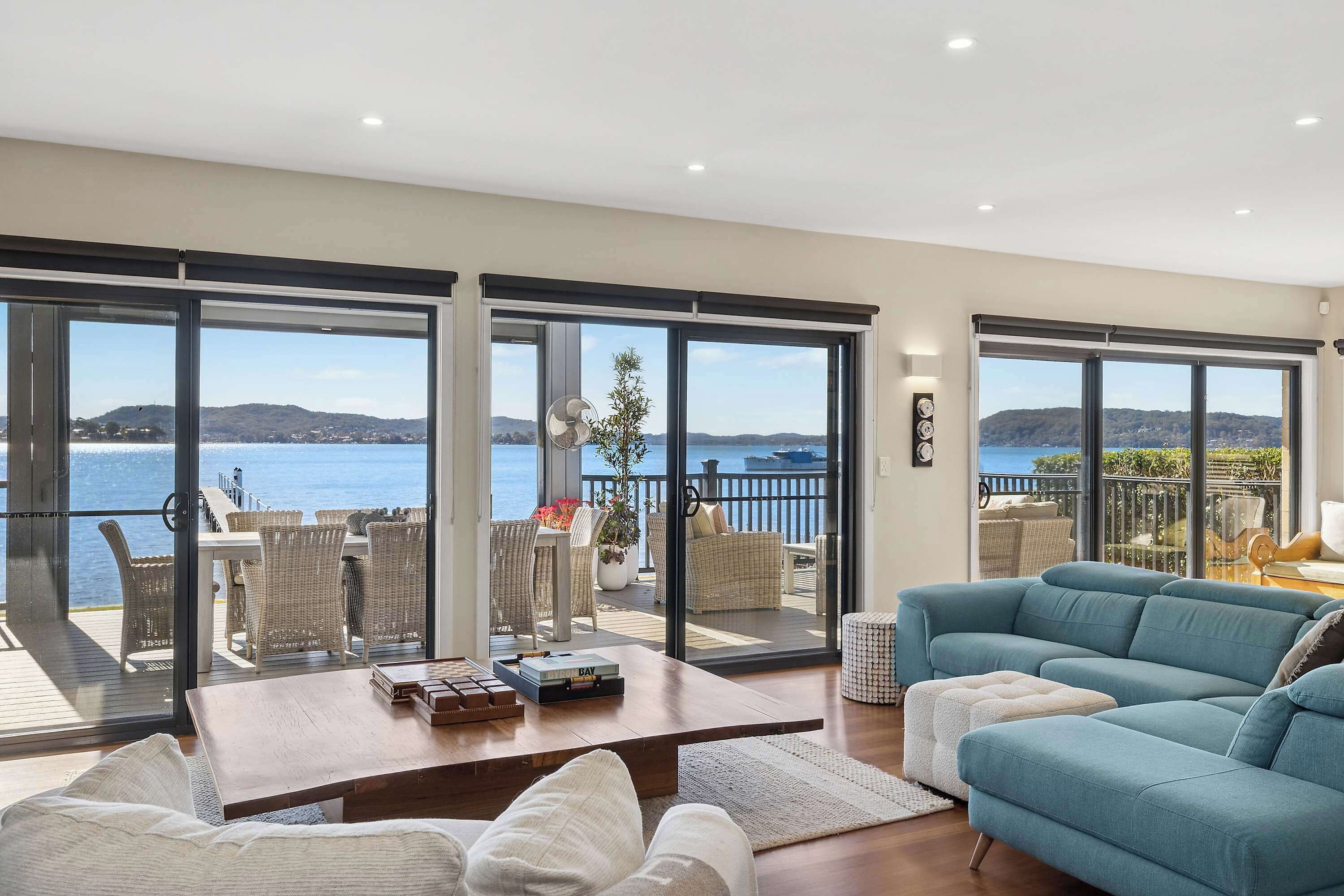 A spacious living area with a large sofa, a coffee table, and a view of the sea through large sliding glass doors.