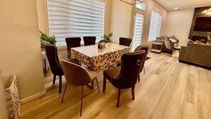 Ein Essbereich mit Tisch und Stühlen, eine Leuchter und ein Wohnzimmer mit Sofa und Fernseher.