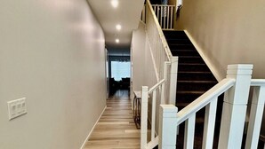 Ein Flur mit Holzboden, weißen Wänden und einer weißen Treppe mit Geländer.