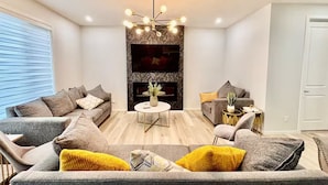 Ein modernes Wohnzimmer mit zwei grauen Sofas, einem runden Couchtisch und einem besonderen Kronleuchter.