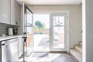 A kitchen with a sliding door leading to a backyard. - 7BR | Patio, BBQ | West Seattle | Sophari Home I (Seattle)