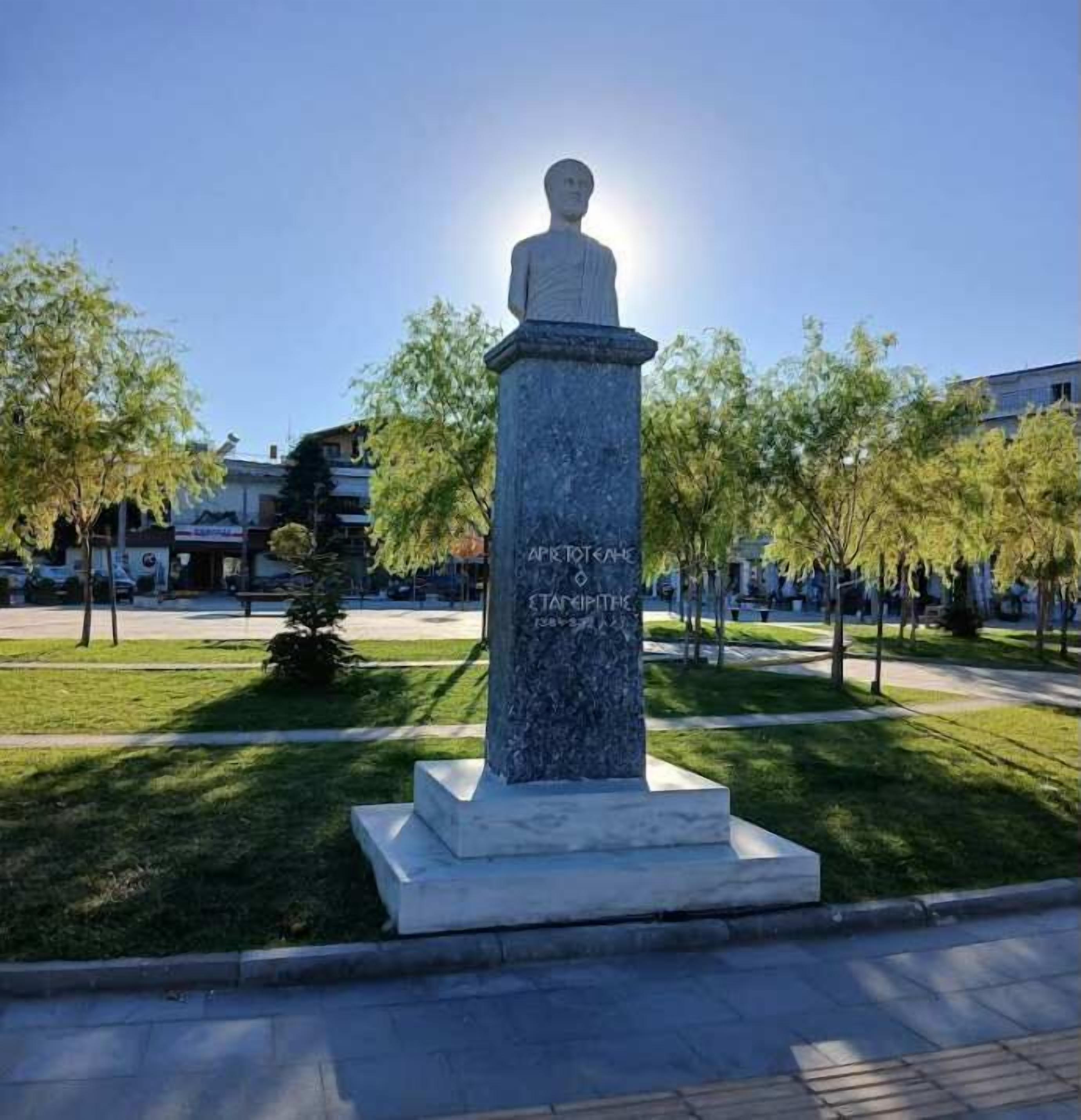 A statue with a pedestal in a park setting.