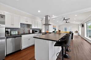 A modern kitchen with white cabinets, a central island, and a bar area with stools. - Lakefront Home with Hot Tub, Private Dock & Ramp (Hot Springs)