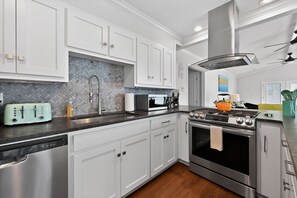 A modern kitchen with white cabinets, a stainless steel dishwasher, a microwave, a stove, and a ceiling fan. - Lakefront Home with Hot Tub, Private Dock & Ramp (Hot Springs)