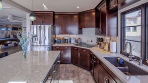 A modern kitchen with dark wood cabinets, stainless steel appliances, and a large island with a marble countertop.