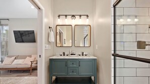 A bathroom with a teal vanity, two mirrors, and a shower with a glass door. - Stylish Townhouse with Game Room, King Suite (Cincinnati)