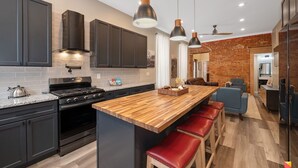 A modern kitchen with dark cabinets, a wooden island, and a built-in oven. - Stylish Townhouse with Game Room, King Suite (Cincinnati)