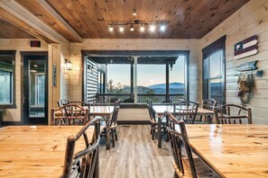 Ein Holzinterieur mit einem großen Tisch und Stühlen, Blick durch die Glastür und einer Flagge an der Wand.