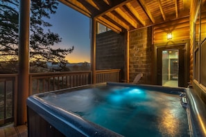 Ein Whirlpool auf einer Holzdiele mit einer Steinmauer und einer Holzbeschichtung.