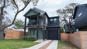 A modern two-story house with a covered front porch, a garage, and a well-maintained lawn. - OmAura Home vibe | Austin Downtown | Games | 4BR (Austin)