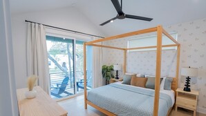 A bedroom with a four-poster bed, a ceiling fan, a nightstand with a lamp, and a view of the outside balcony. - OmAura Home vibe | Austin Downtown | Games | 4BR (Austin)