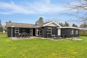 Een tweelaags huis met een terras, een barbecueplek en een klein dek.