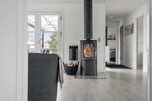 A modern living room with a wood-burning stove, a grey sofa, and a black storage basket. - Newly renovated holiday home 150 m from fjord (Farsø)