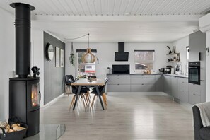 A modern kitchen with a central island, a built-in stove, and a dining area with chairs. - Newly renovated holiday home 150 m from fjord (Farsø)