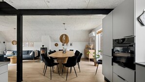 A modern kitchen with a central island, black chairs, and a dining table. - Holiday home with spa, sauna and hot tub (Farsø)