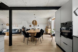 A modern kitchen with a central island, black chairs, and a dining table. - Holiday home with spa sauna and hot tub (Farsø)