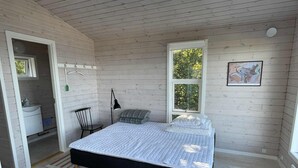 A bedroom with a bed, a chair, a desk, a window, and a painting on the wall. - Holiday home with stunning Baltic Sea view (Hasle)