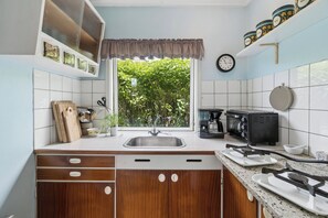 Eine Küche mit Fenster, Spüle, Toaster und einer Uhr an der Wand.
