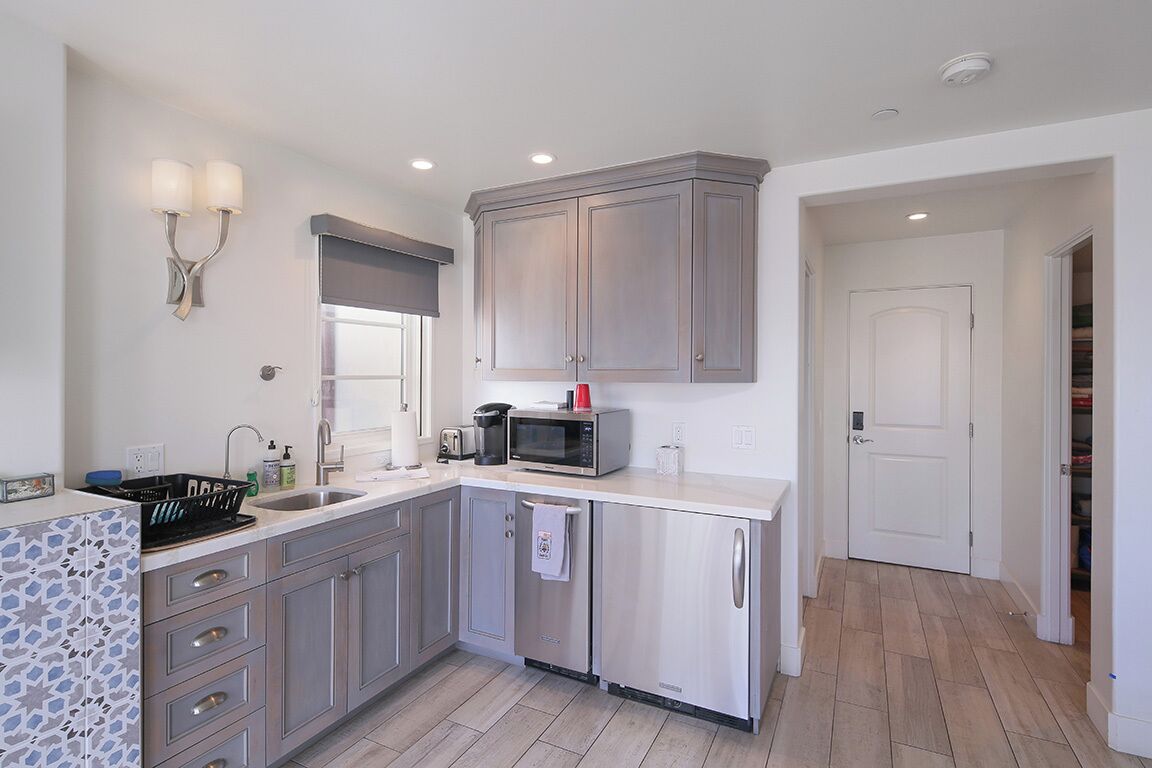A modern kitchen with grey cabinets, a microwave, and a sink.