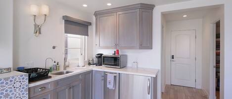 A modern kitchen with grey cabinets, a microwave, and a sink.