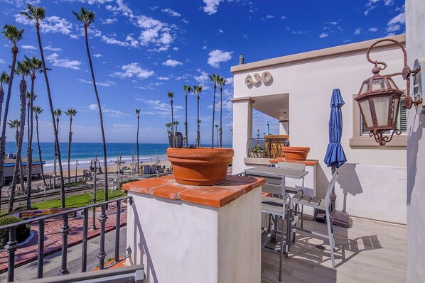 Une terrasse sur le toit avec vue sur la plage, une enseigne portant le numéro 630, une table avec des chaises et un pot de fleurs.