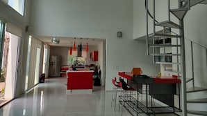 Eine geräumige Küche mit Kochinsel, moderner Pendelleuchte und einer Wendeltreppe.