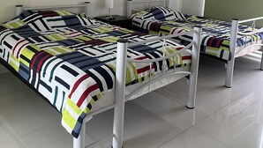 Ein Zimmer mit zwei Betten, einem Deckenventilator und einer grünen Wand.