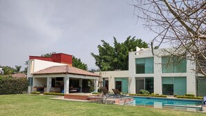 Ein modernes Haus mit Pool, einer überdachten Terrasse und einem gepflegten Rasen.