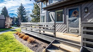Ein modernes Haus mit einer Holzdielen-Terrasse, einer Haustür mit einem Kranz und der Hausnummer 1259 an der Seite.