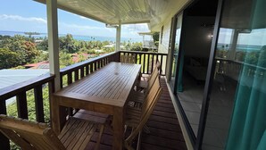 A wooden deck with a table and benches, overlooking a scenic view of the ocean and tropical landscape. - Luna's Home Raiatea (Tumaraa)