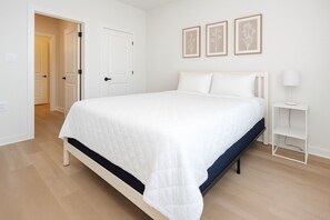 Ein Schlafzimmer mit einem Bett, weißen Wänden und einer Tür zu einem anderen Raum.