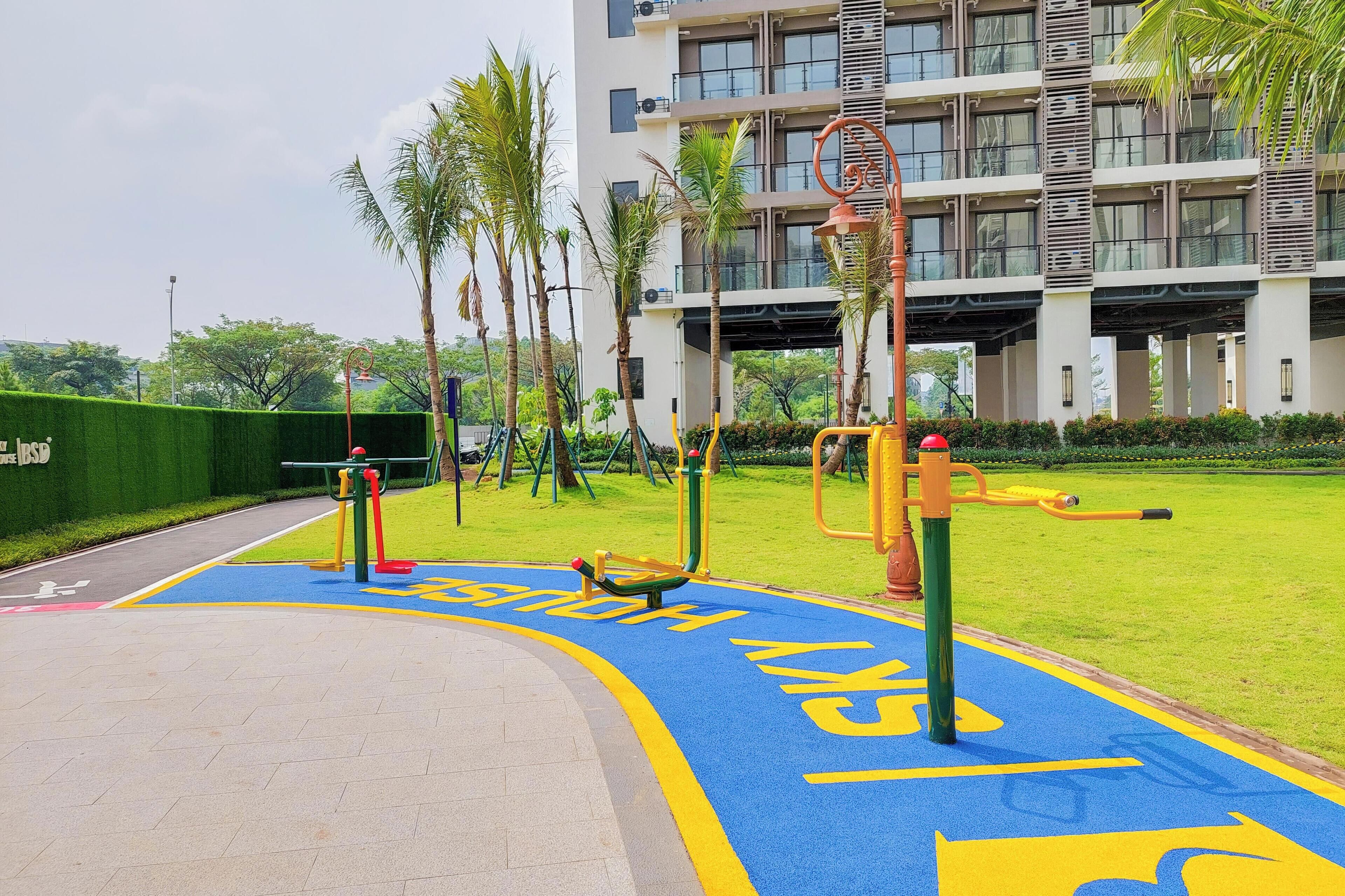 A playground with exercise equipment and a blue bike lane.