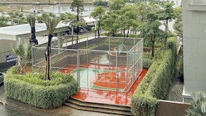 Un terrain de basket entouré d’une clôture métallique, avec des marches menant au terrain.