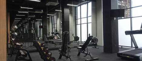 A gym with various exercise equipment, large windows, and a mirrored wall.