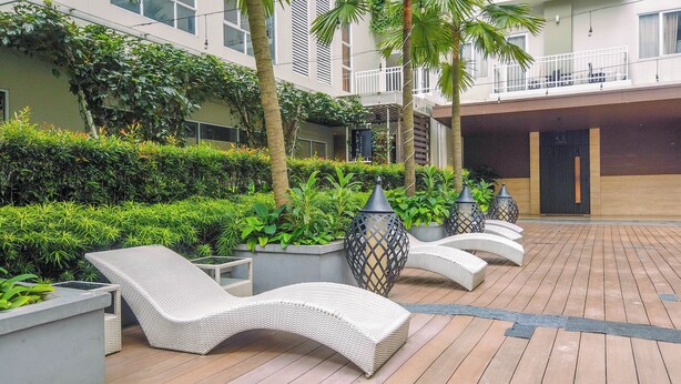 Une cour avec des fauteuils, des plantes en pot et un bâtiment doté de balcons.